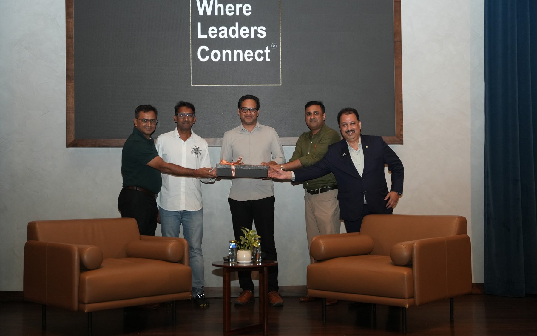 Stage group presenting a gift under Where Leaders Connect screen