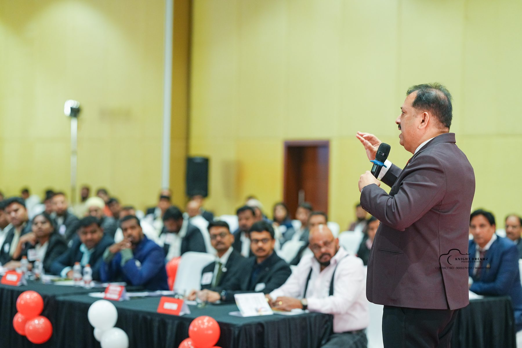 Uday Shetty addressing a large seated audience with a microphone at BNI Emerald Grand Launch